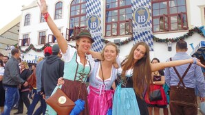 A group of people in traditional attire in front of a building with 'MÜNCHEN' banners. - Munich Camping Glamping and Dorms (Munich)