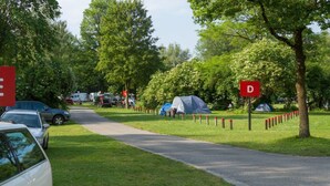 A campsite with designated parking areas marked by red signs, tents, and RVs. - Munich Camping Glamping and Dorms (Munich)