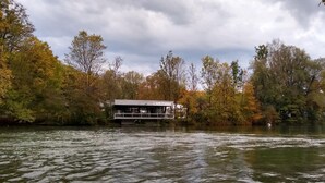 A riverside cabin with a deck, surrounded by autumn foliage. - Munich Camping Glamping and Dorms (Munich)