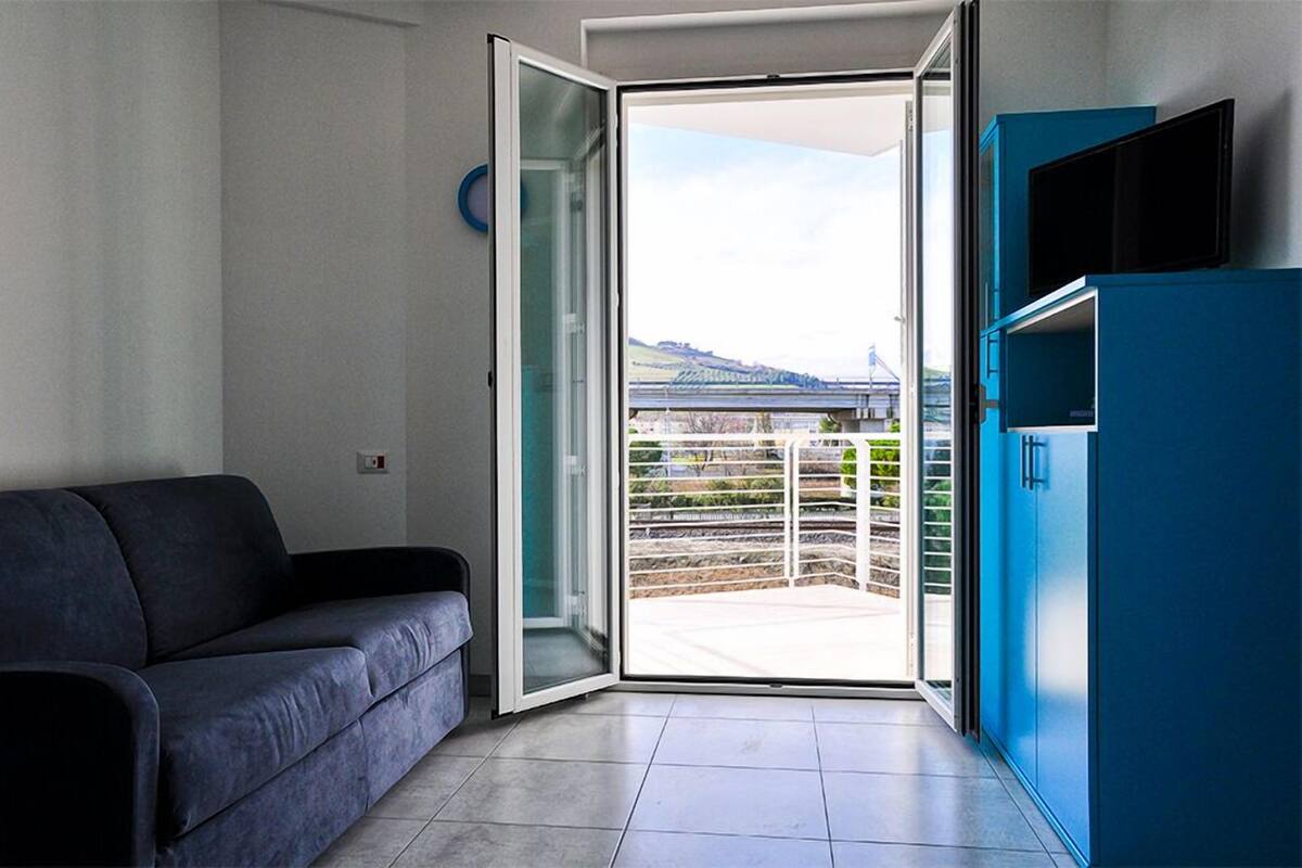 A modern living room with a sofa, a sliding glass door leading to a balcony, and a blue cabinet.