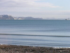 A calm sea with a rocky shoreline and distant mountains. - The Beach House (Weymouth)