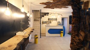 A modern interior with a wooden reception desk, a staircase, and a unique brick wall decoration. - Urban Pop Hostel & BnB (Catania)