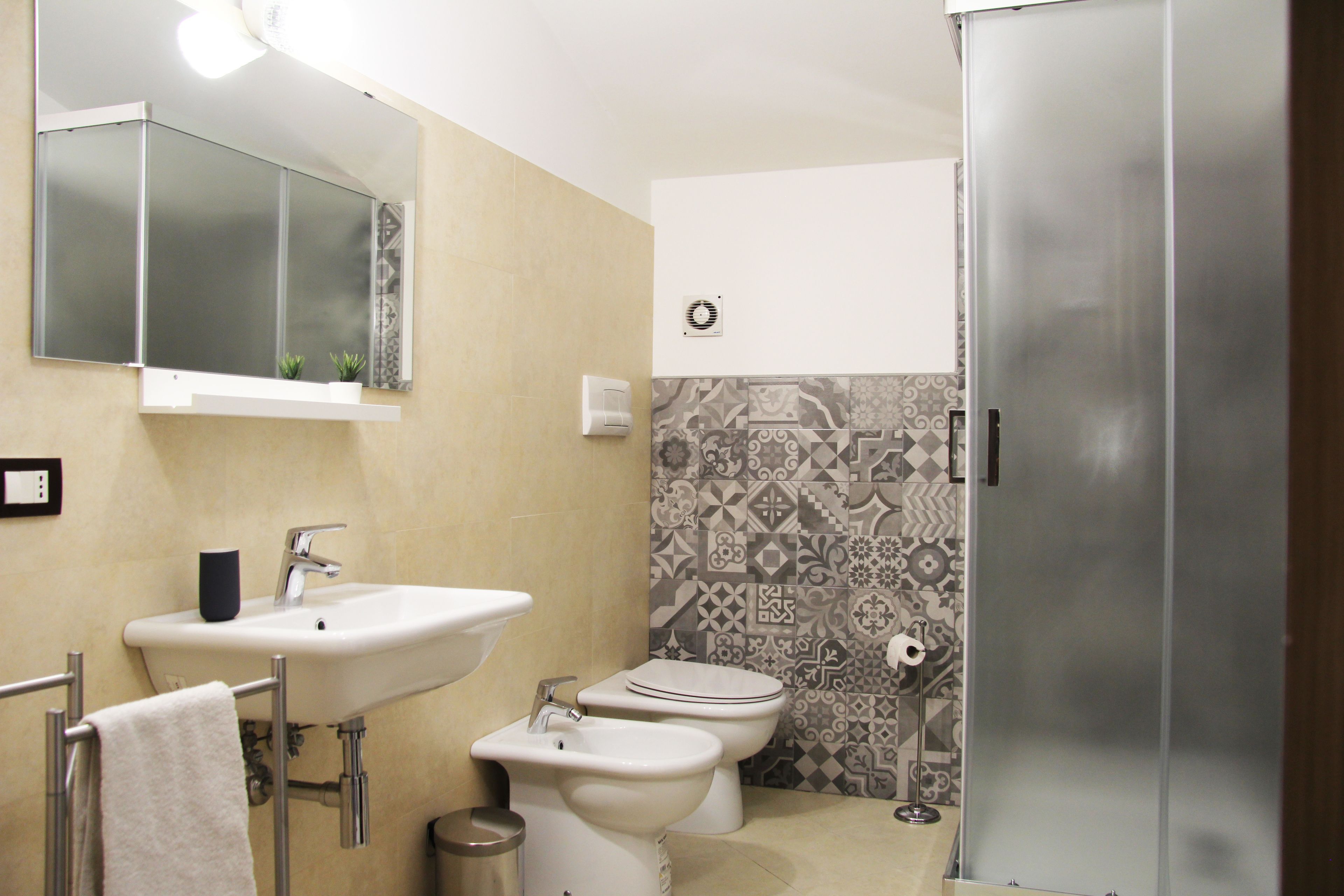 A bathroom with a sink, two toilets, a bidet, a mirror, and a shower.