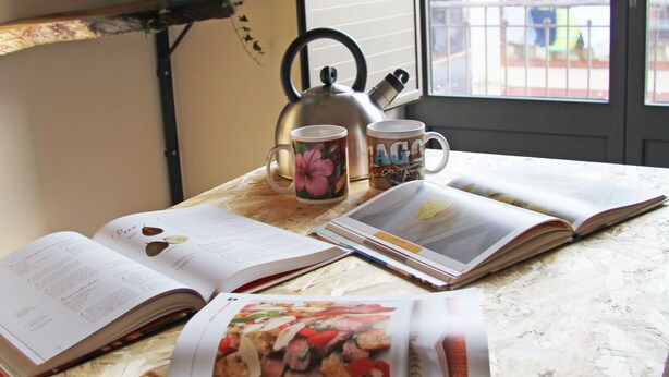 A table with open books, a kettle, and a mug. - Urban Pop Hostel & BnB (Catania)