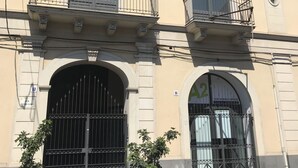 A multi-story building with balconies, large arched doors, and a sign indicating a communication business. - Urban Pop Hostel & BnB (Catania)
