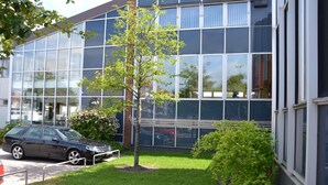 Moderni rakennus, jossa on suuret ikkunat ja pysäköintialue.