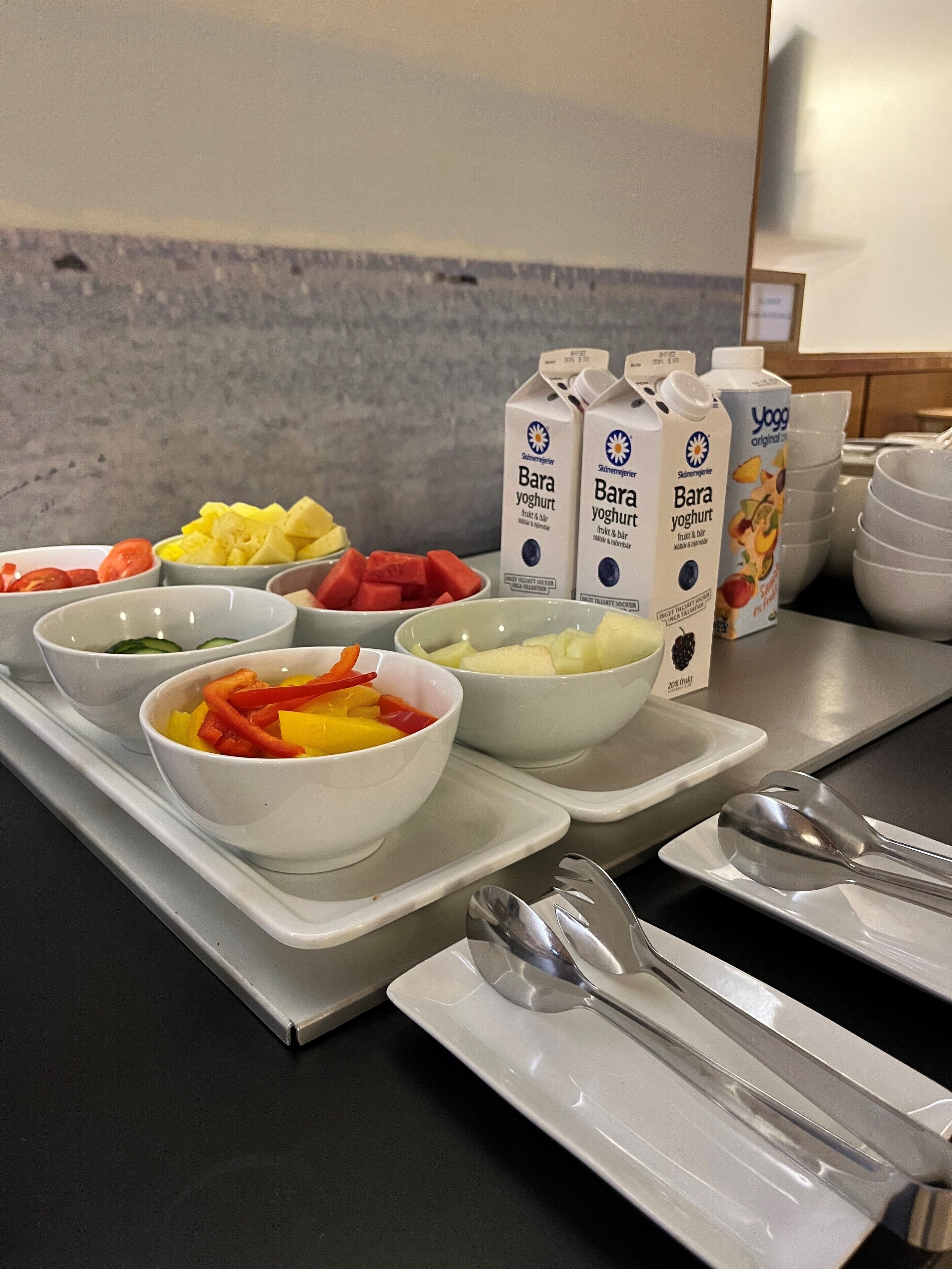 A breakfast buffet with various fruit bowls and containers of Bara yoghurt.