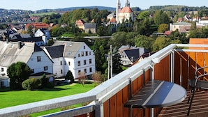 A balcony with a view of a town, including a church with two towers. - Gästezimmer & Ferienwohnung Berge (Schirgiswalde-Kirschau)