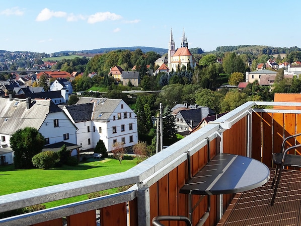 A balcony with a view of a town, including a church with two towers.