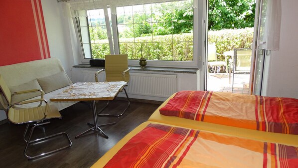 Una habitación con cama, una silla, una mesa y un ventanal con vistas a zonas verdes.