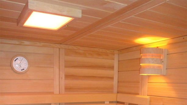 A sauna with wooden benches, a wooden bucket, and a wall-mounted clock. - Gästezimmer & Ferienwohnung Berge (Schirgiswalde-Kirschau)