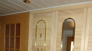 A room with a wooden door, a tall mirror, and a small glass console table. - Gästezimmer & Ferienwohnung Berge (Schirgiswalde-Kirschau)