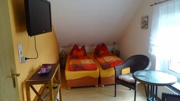 A room with two beds, a TV, a table, and a chair.