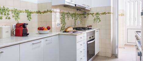 A modern kitchen with white cabinets, a gas stove, and a coffee maker.