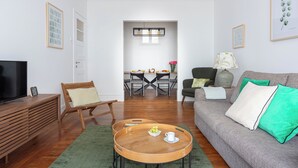 Un salon moderne comprenant un canapé, une table basse en bois, un téléviseur et un coin repas avec une table et des chaises.