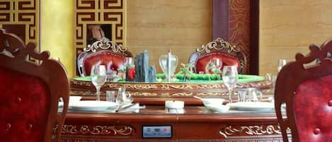 Una mesa de comedor con sillas ornamentadas, un mantel verde y un centro de mesa decorativo.