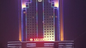 A tall building with vertical light strips and a sign at the base. - Tiangui Zhongzhou International Hotel (Neixiang)