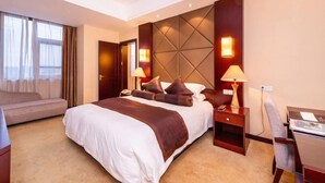 A hotel room with a large bed, two bedside tables with lamps, a desk, and a sofa. - Tiangui Zhongzhou International Hotel (Neixiang)