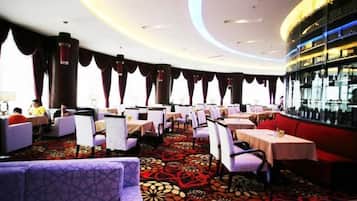 Un restaurante con mesas y sillas redondas, una alfombra estampada y una zona de bar.