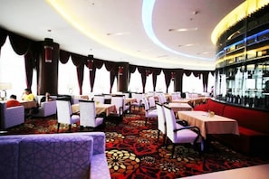 A restaurant with round tables and chairs, a patterned carpet, and a bar area. - Tiangui International Hotel (Neixiang)