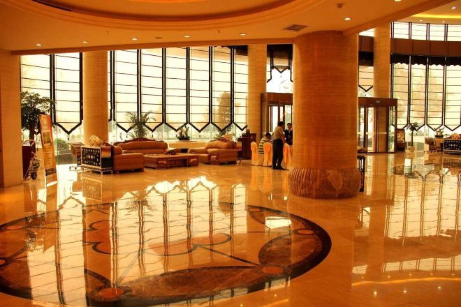 A spacious lobby with a polished floor, large windows, and a central seating area.
