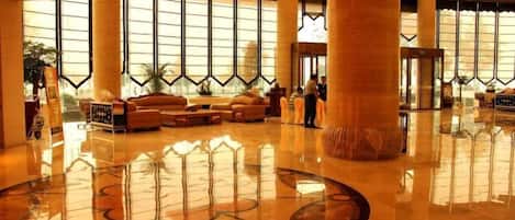 A spacious lobby with a polished floor, large windows, and a central seating area.