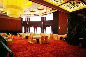 A banquet hall with round tables, chairs, and a red carpeted floor. - Tiangui International Hotel (Neixiang)