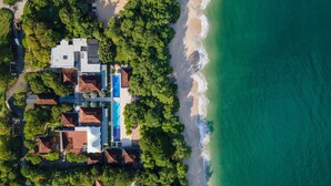 Vista aérea de una propiedad costera con piscina, varias edificaciones y una playa.