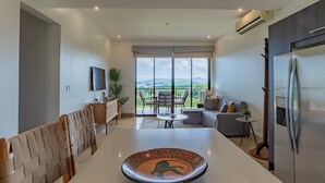 Una sala de estar moderna con un ventanal grande, un comedor y una cocina.