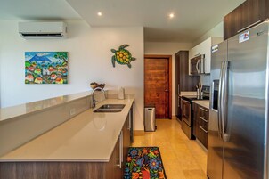 Una cocina moderna con una isla grande, electrodomésticos de acero inoxidable y una puerta de madera.