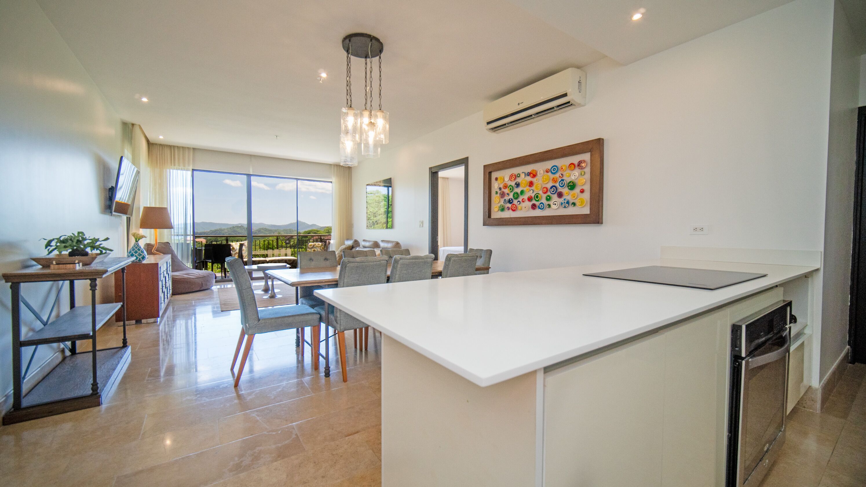 A spacious living area with a large kitchen island, a dining table, and a seating area with a view of the outdoors.