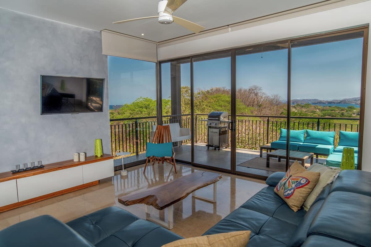 A modern living room with a large glass door leading to a balcony.