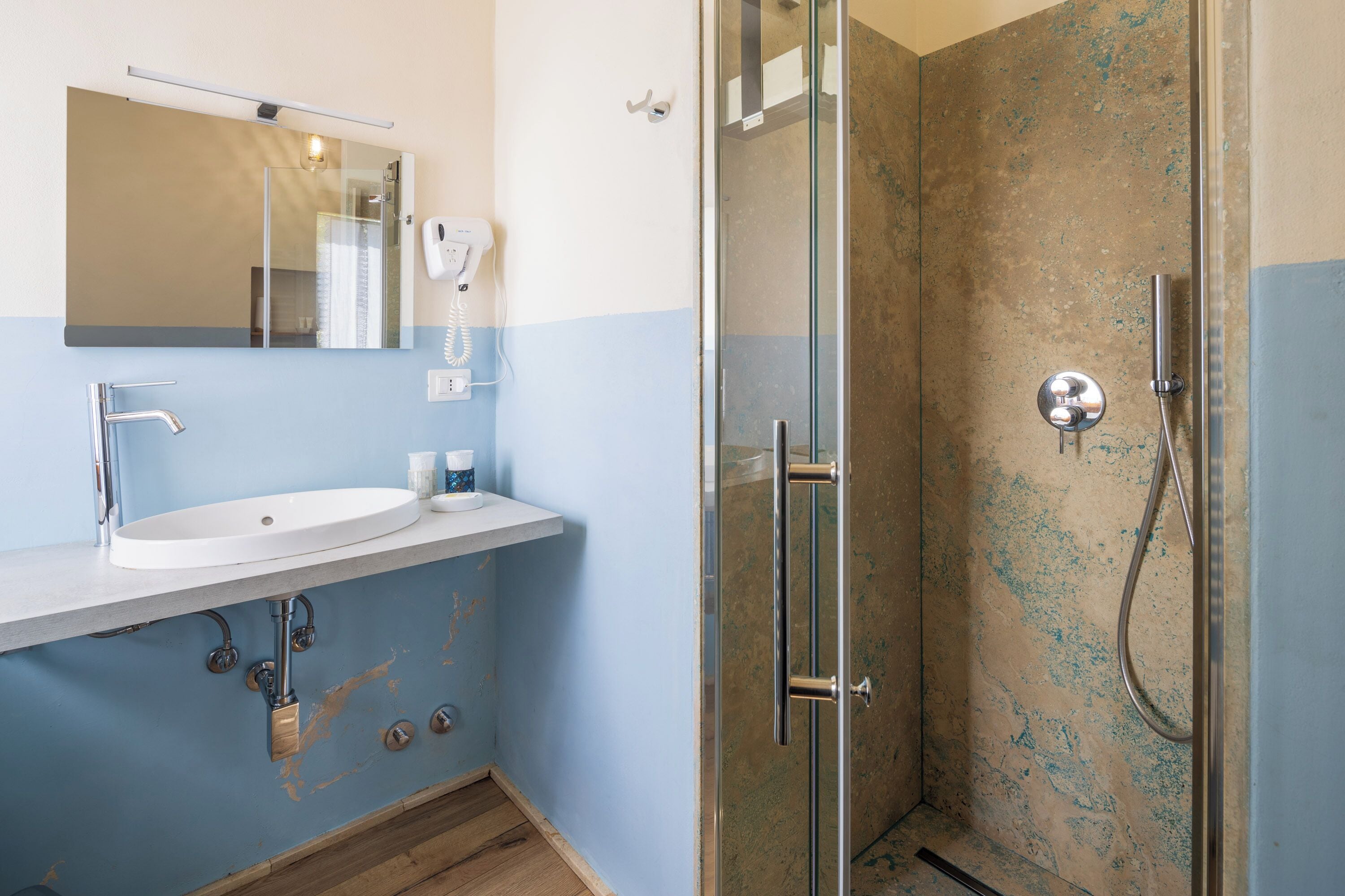 A bathroom with a sink, mirror, and glass-enclosed shower.