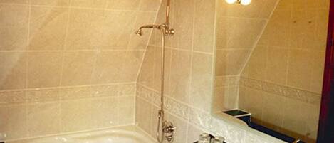 A bathroom with a bathtub, a sink, and a large mirror with lights.