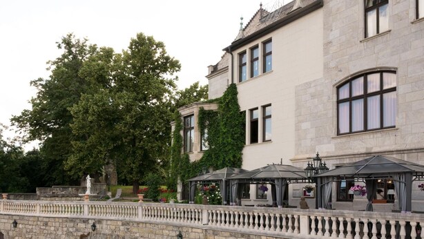 A stone building with large windows and a garden with a fountain and seating area. - Schlosshotel Zum Markgrafen (Quedlinburg)