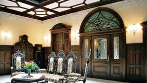 A room with ornate wooden furniture, including a large arched doorway and a round table with chairs. - Schlosshotel Zum Markgrafen (Quedlinburg)