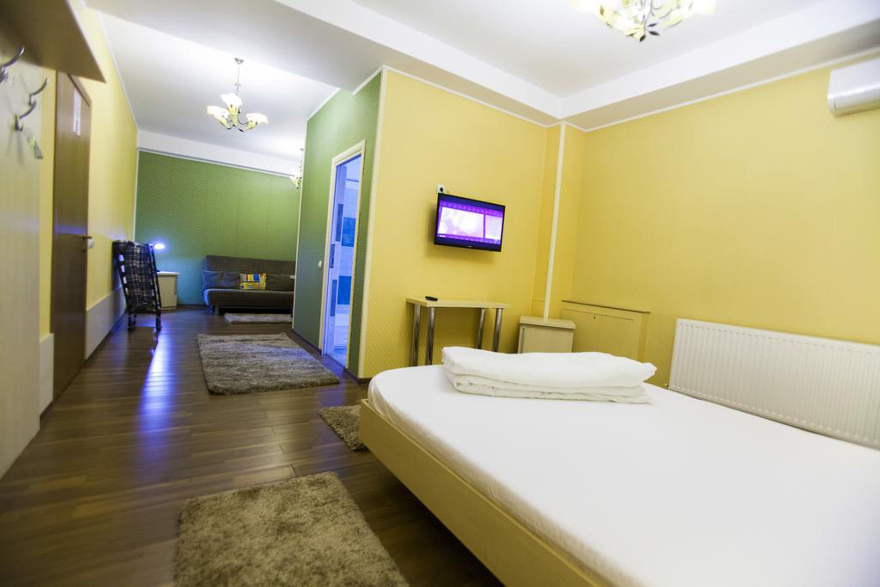 Habitación de hotel con cama, televisión montada en la pared y un pasillo que conduce a otra habitación.
