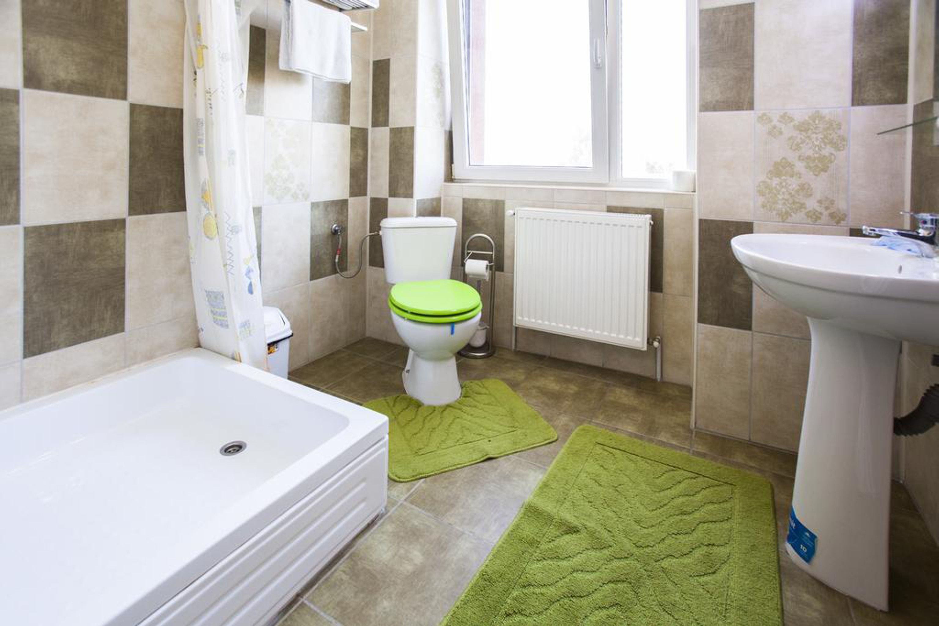 Un baño con una bañera blanca, un inodoro verde y un lavabo blanco.