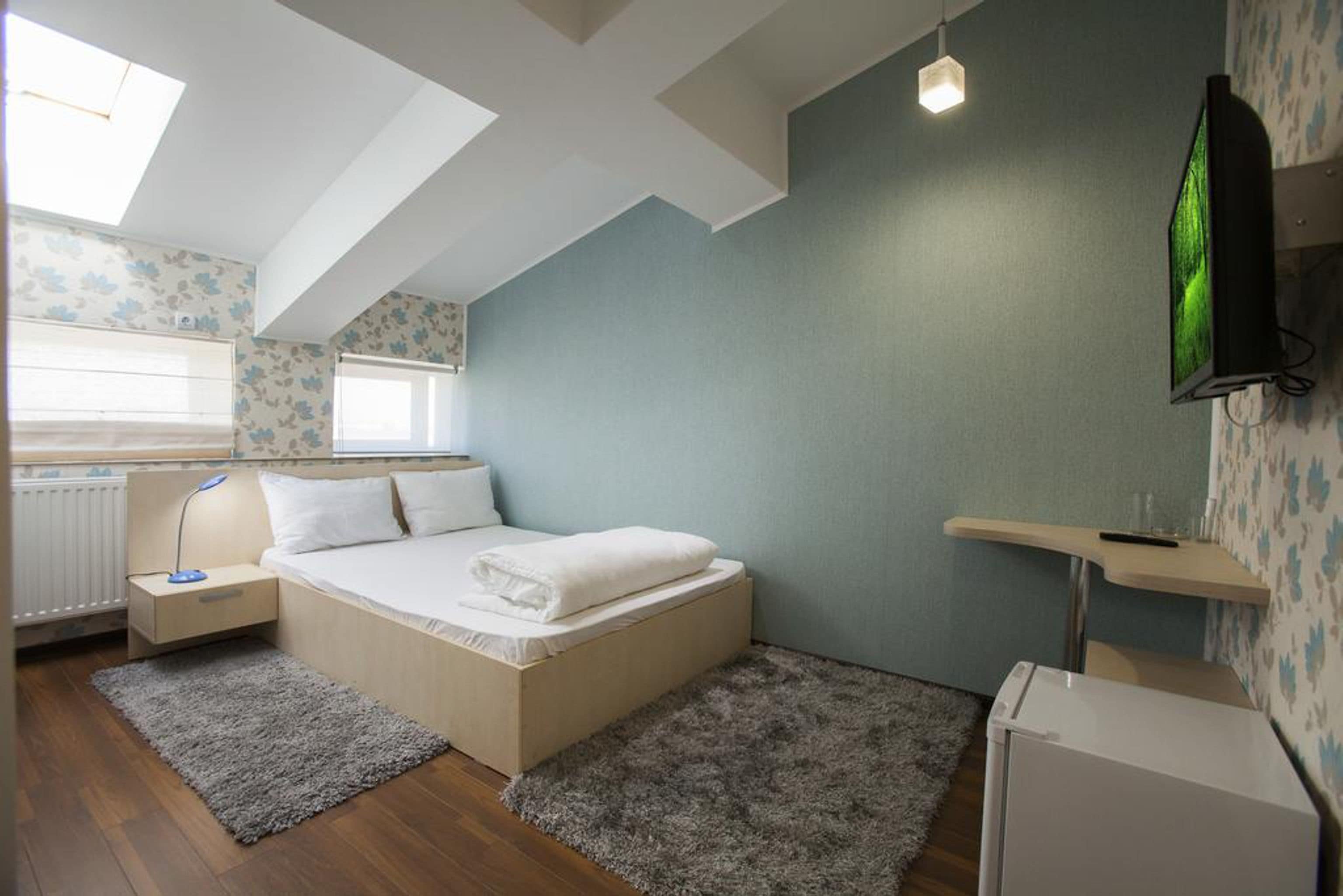 Un dormitorio con cama, mesitas de noche, escritorio, radiador y televisor.