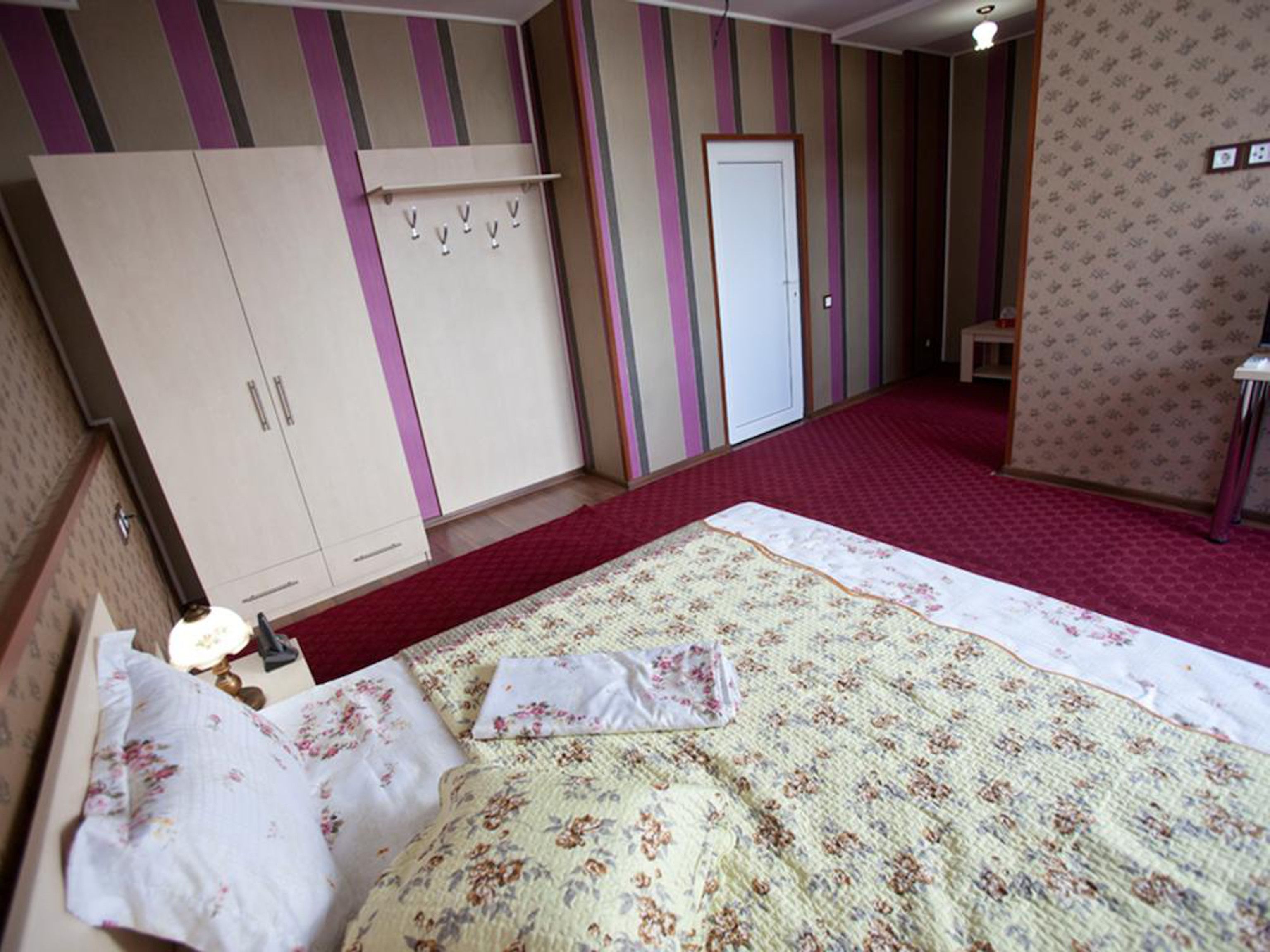 Quarto com cama, guarda-roupa e porta.