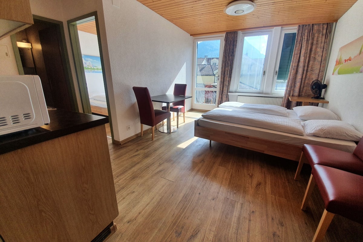 A hotel room with a wooden ceiling, a bed, a desk, and a chair.