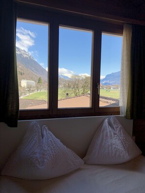 A room with a bed and a window overlooking a mountainous landscape. - Central Beauty Scenery Apartment (Interlaken)