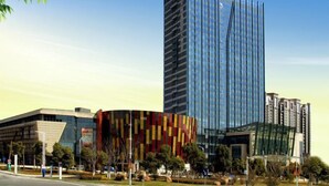 Un edificio moderno con fachada de vidrio y una estructura cercana con llamativas rayas rojas y amarillas.