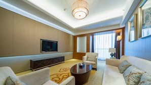 Una sala de estar moderna con un televisor de pantalla plana, un conjunto de sofá, una mesa de centro y un amplio ventanal con cortinas.