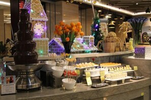 A buffet area with a variety of food items, a decorative gingerbread house, and a chocolate fountain. - Dynasun International Hotel (Nantong)