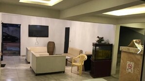 A modern living room with a sofa, armchairs, a flat-screen TV, and a decorative cabinet. - Hotel Residence Vera (Abidjan)