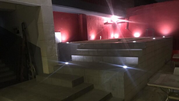 A stone staircase leading up to a platform with a railing, surrounded by walls with red lighting. - Hotel Residence Vera (Abidjan)
