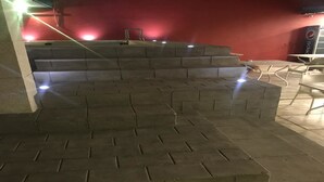 A set of outdoor steps leading to a seating area with a red wall and a Pepsi sign in the background. - Hotel Residence Vera (Abidjan)