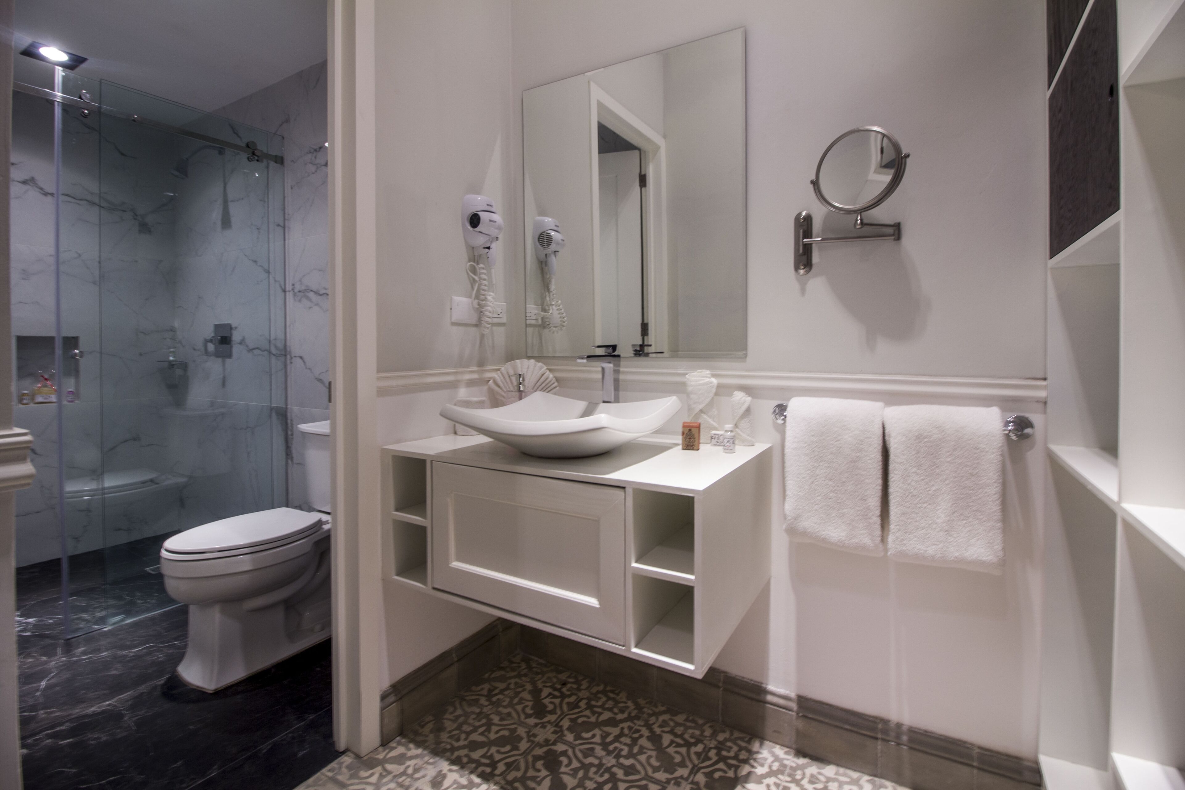 A modern bathroom with a glass-enclosed shower, a white sink, and a large mirror.
