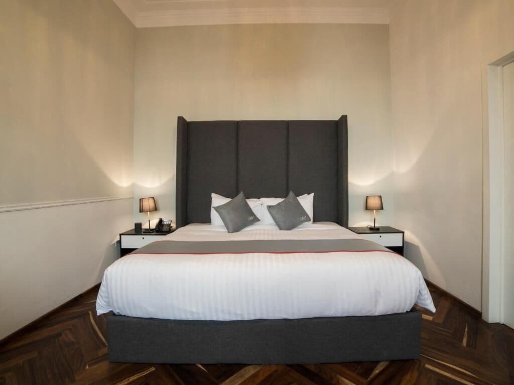 A neatly made bed with a dark headboard, white bedding, and two bedside lamps.